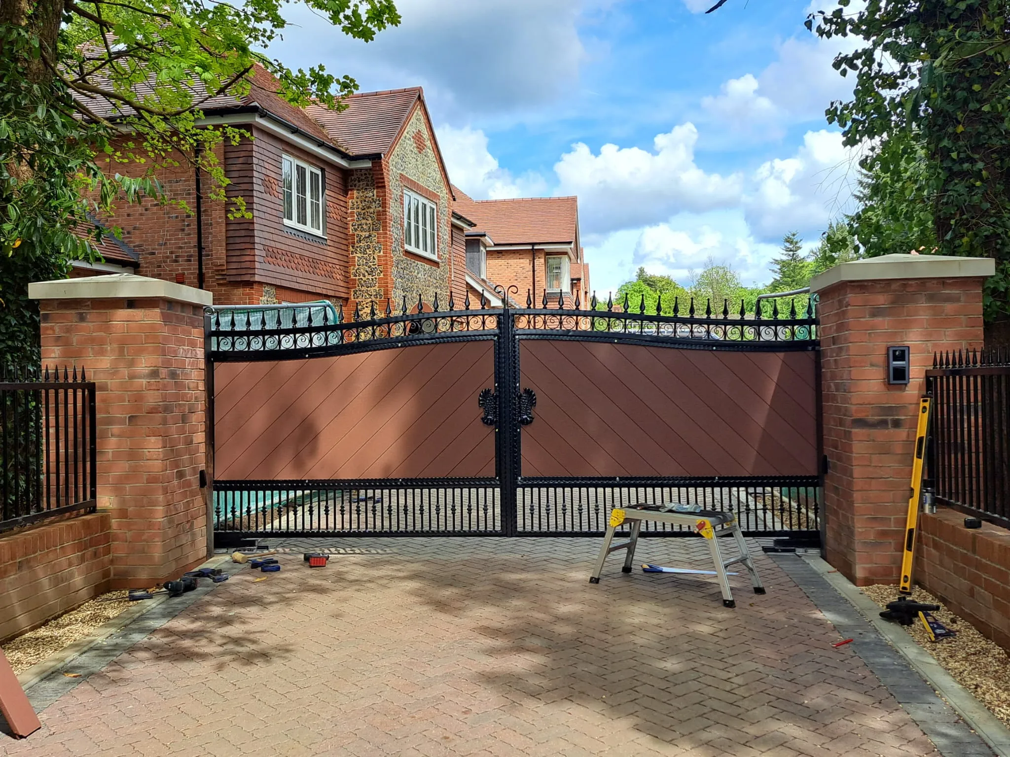 A brick driveway with a fence and a bench.