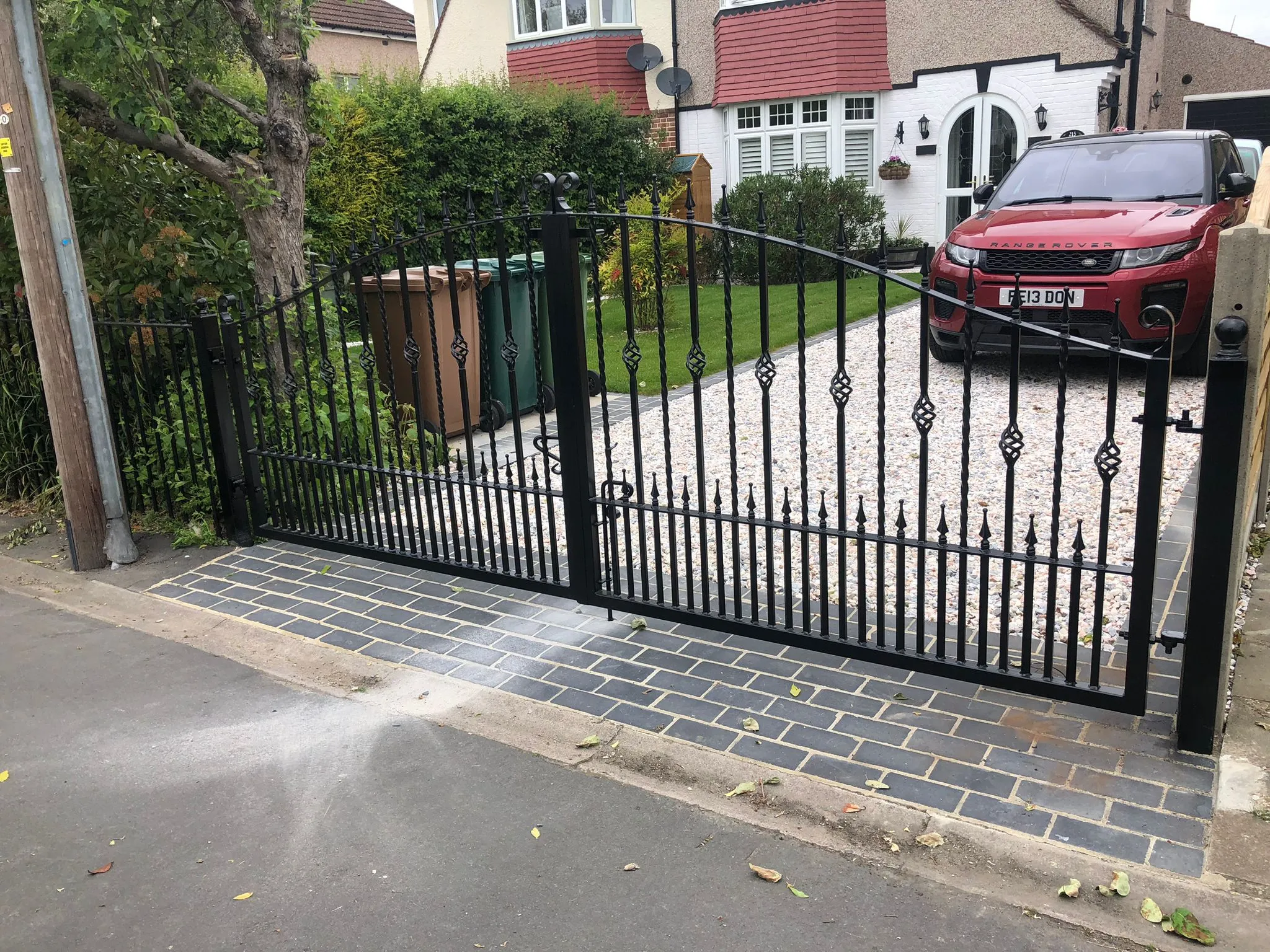 A red car parked in front of a black gate.