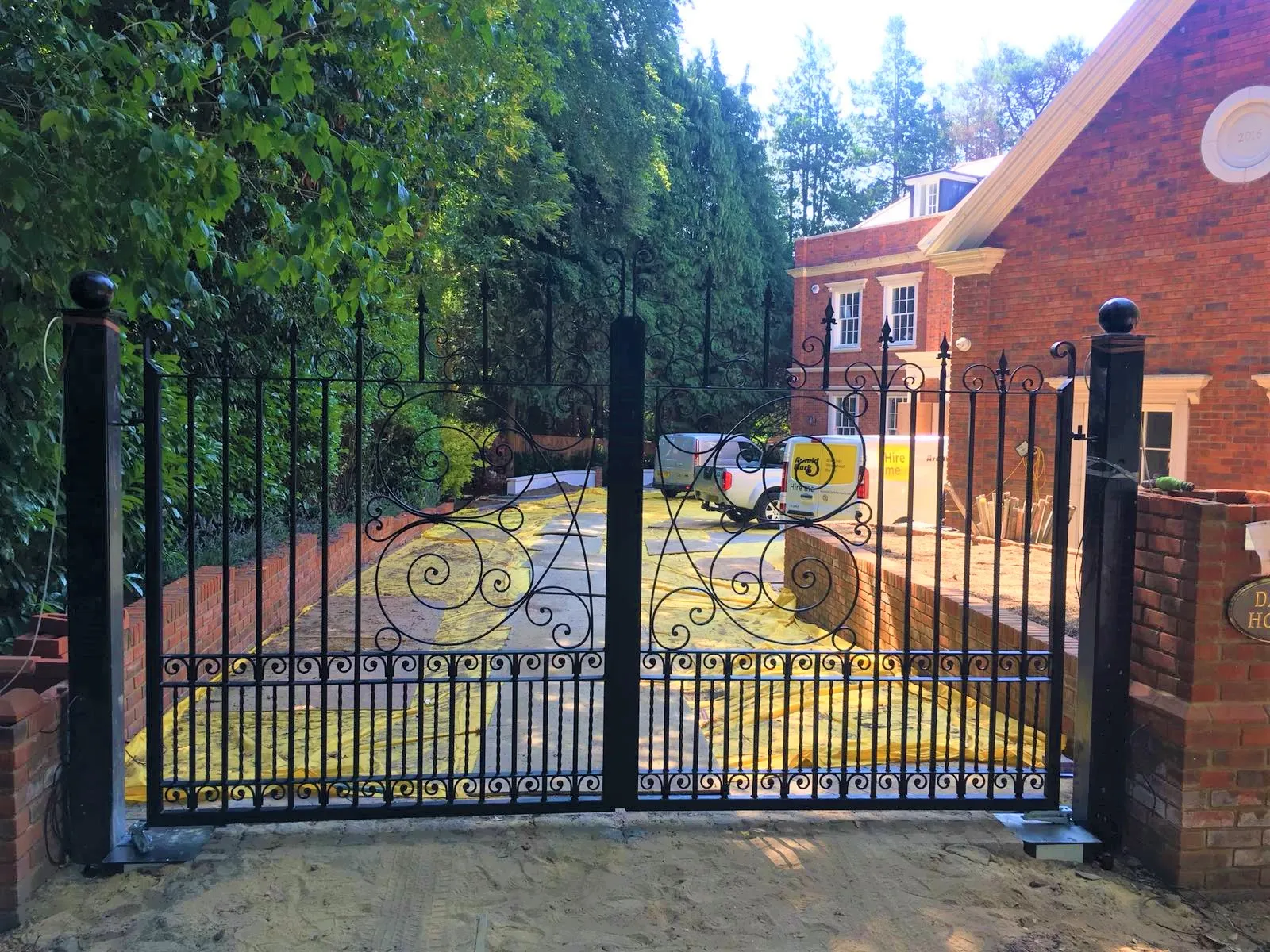 An iron gate with a driveway in the background.