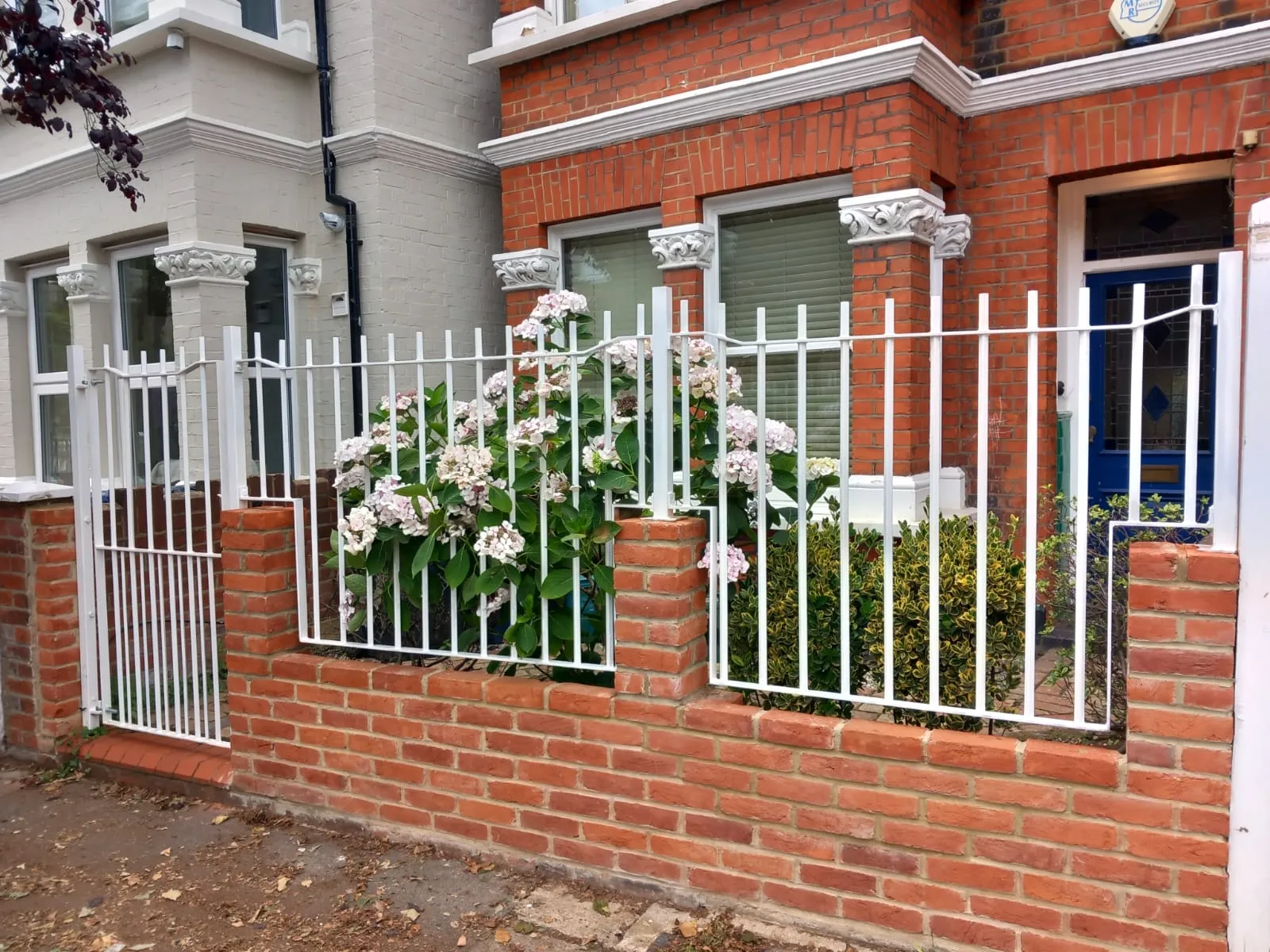 A red brick house with white iron fence.