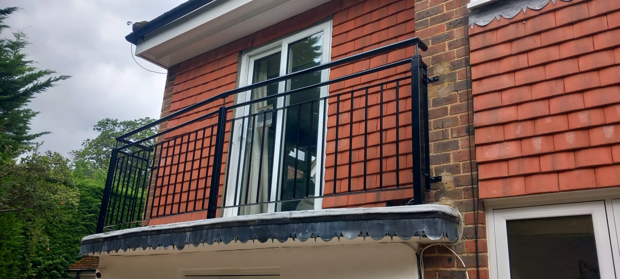 A red brick building with a black metal balcony.