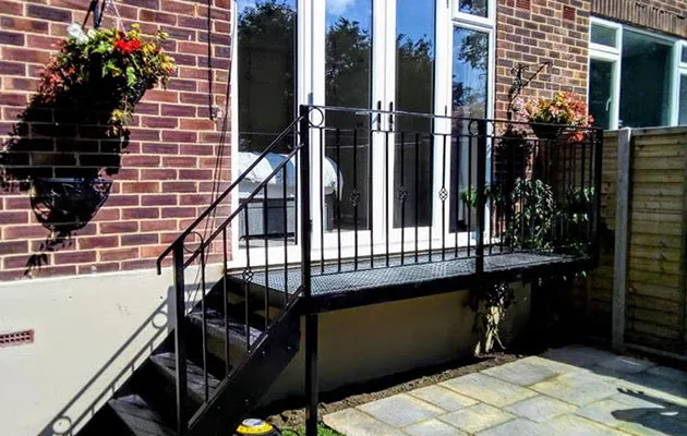 A house with a black railing and a white door.